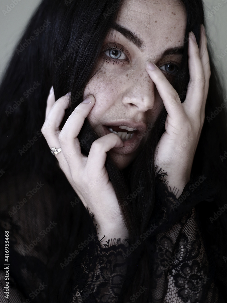 Foto de a young gothic girl pale with freckles holding her face in fear ...