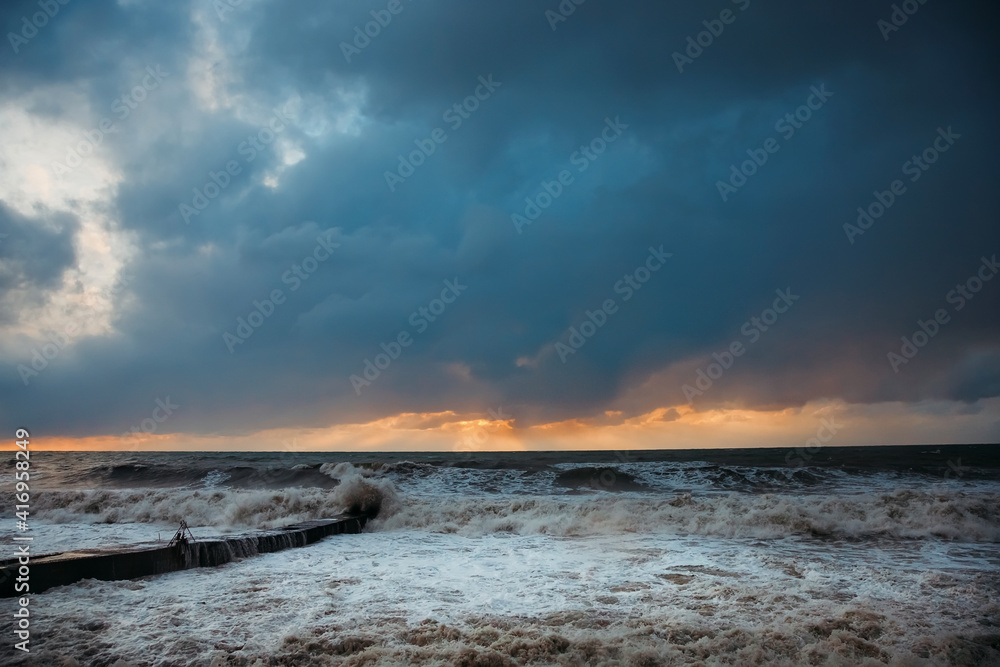 Storm waves near the shore on the beach. In the foreground, breakwaters. Storm waves near the shore on the beach. In the foreground, breakwaters.