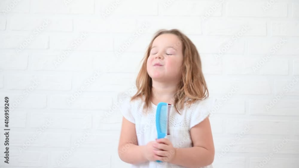funny girl 4 years old singing and dancing with a comb like with a microphone at home on a white background funny girl 4 years old singing and dancing with a comb like with a microphone at home on a white background