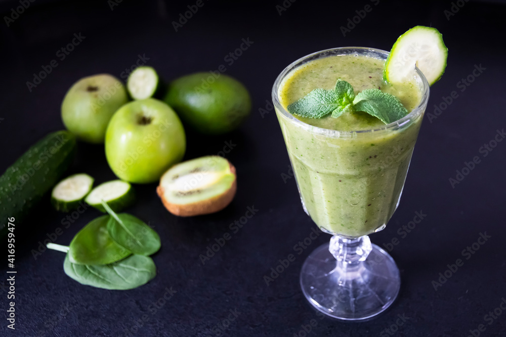 Delicious green smoothie and fresh fruits on black table. Healthy green smoothie with banana, spinach, avocado, apple and mint in a glass. Vegan food. Delicious green smoothie and fresh fruits on black table. Healthy green smoothie with banana, spinach, avocado, apple and mint in a glass. Vegan food.
