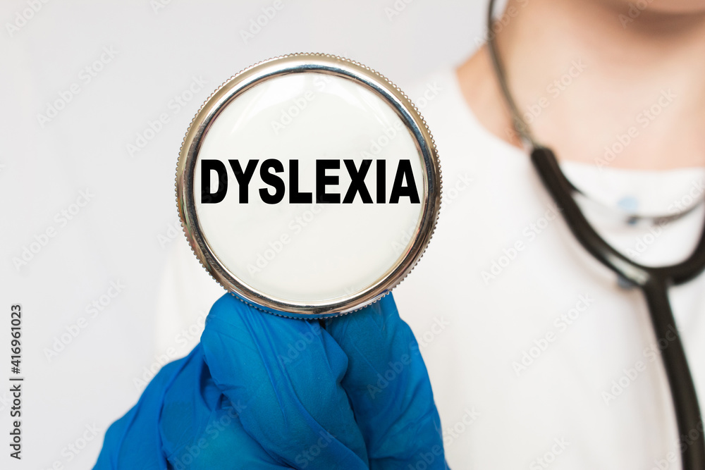 The doctor's blue - gloved hands show the word DYSLEXIA - . a gloved hand on a white background. Medical concept. the medicine The doctor's blue - gloved hands show the word DYSLEXIA - . a gloved hand on a white background. Medical concept. the medicine