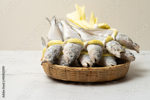 A salted yellow string of dried yellow corvina was placed in a bamboo basket. photo