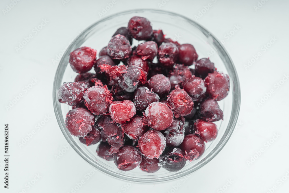 Frozen cherries in a glass bowl top view on white background Frozen cherries in a glass bowl top view on white background