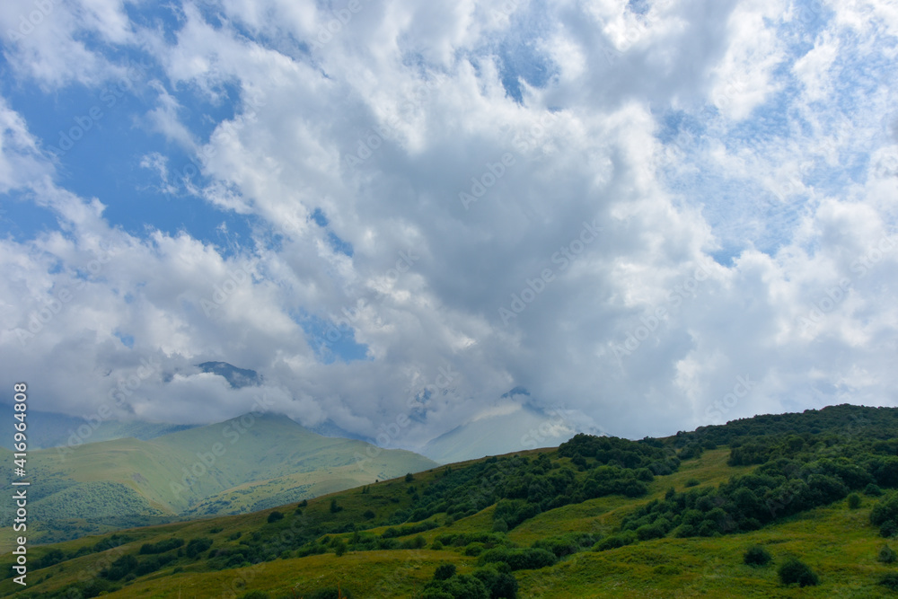 Beautiful mountain peaks of the North Caucasus against the backdrop of a blue cloudy sky. Republic of North Ossetia - Alania