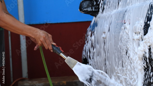 worker car cleaning  spraying and wiping  at his workplace