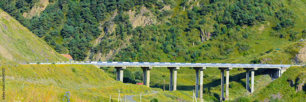Automobile bridge in the vicinity of the village of Zaramag. Mountains of the North Caucasus. Hot summer day. Republic of North Ossetia - Alania Automobile bridge in the vicinity of the village of Zaramag. Mountains of the North Caucasus. Hot summer day. Republic of North Ossetia - Alania