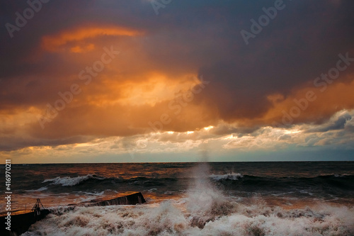 Abstract and colorful storm clouds. Sea sunset. A storm at sea. The waves hit the shore.