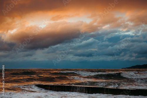 Abstract and colorful storm clouds. Sea sunset. A storm at sea. The waves hit the shore.