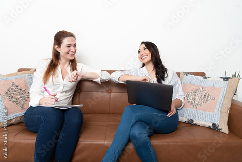 Two beautiful young business women celebrate during a meeting.
