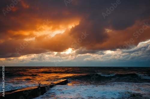 Abstract and colorful storm clouds. Sea sunset. A storm at sea. The waves hit the shore.