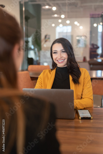 Beautiful young Latina business woman using computer while in meeting. 