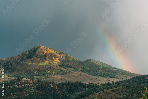 Colorful mountain peak with rainbow during summer.