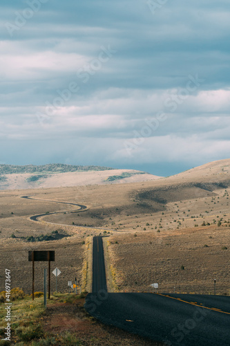 Winding asphalt road in dry hilly grasslands of Utah.