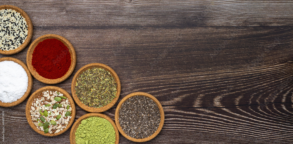 Top of view photography of different spices and seeds. Small bowls made from cork tree containing matcha tea, paprika, powdered red paper, sunflower seeds, chia, French herbs. Top of view photography of different spices and seeds. Small bowls made from cork tree containing matcha tea, paprika, powdered red paper, sunflower seeds, chia, French herbs.
