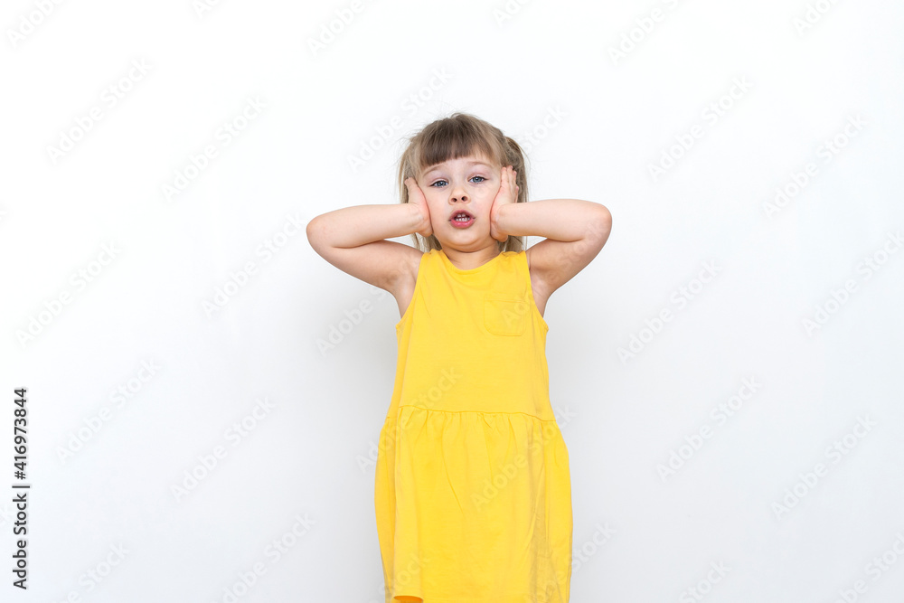 emotional caucasian child girl in a yellow dress grabbing by the head and shocked emotional caucasian child girl in a yellow dress grabbing by the head and shocked