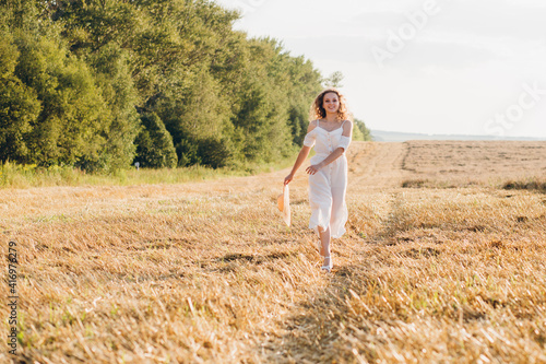 Girl with long curly hair poses in a wheat field