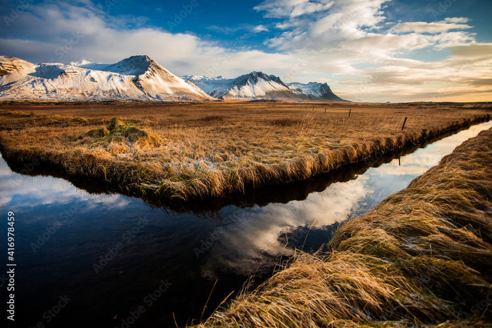 Snowy mountains and river during sunset in Iceland.