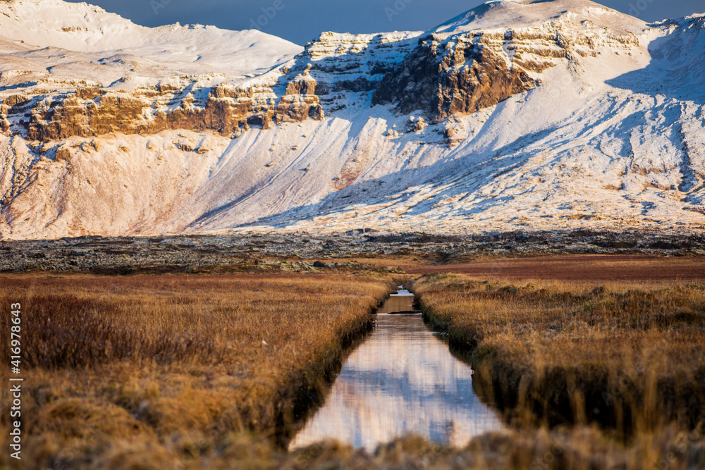 Snowy mountains and river during sunset in Iceland.