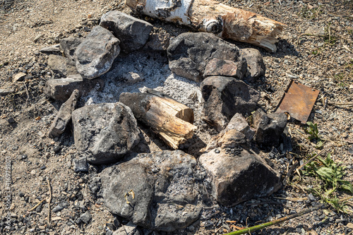 Gray and brown big stones and birch trunk for a bonfire are in a fireplace in the forest
