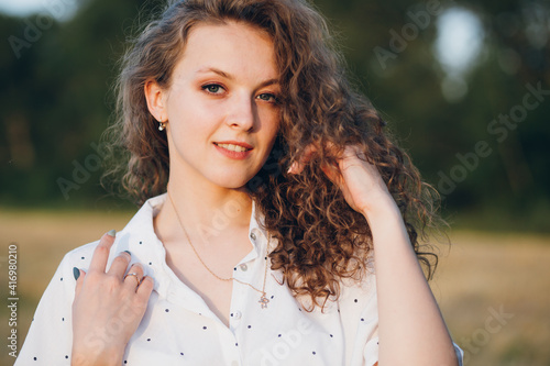Girl with long curly hair poses in a wheat field
