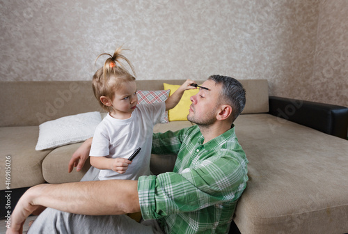 a little girl does makeup to her father during games together.