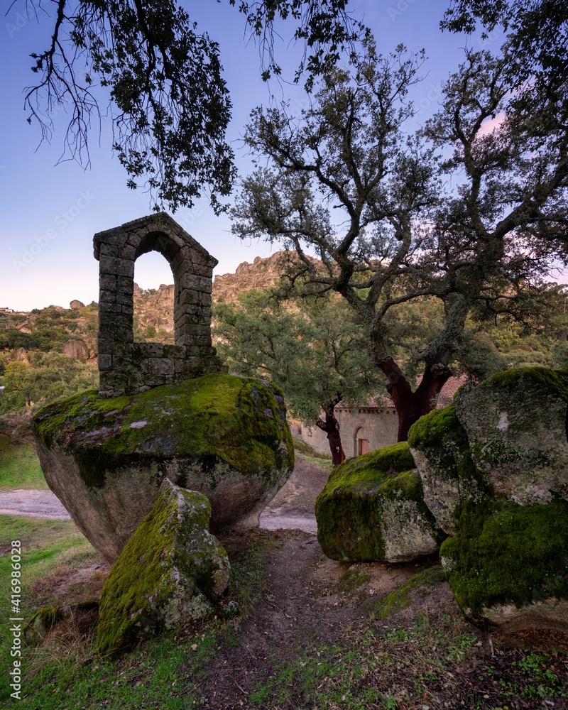 Ancient ruin stone structure building covered with moss near Sao Pedro chapel with trees and boulder landscape in Monsanto, Portugal