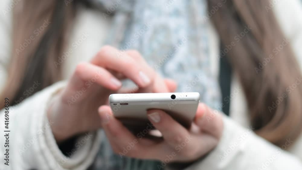Close up of smartphone in hands of caucasian young businesswoman while tapping and scrolling on screen front view Close up of smartphone in hands of caucasian young businesswoman while tapping and scrolling on screen front view