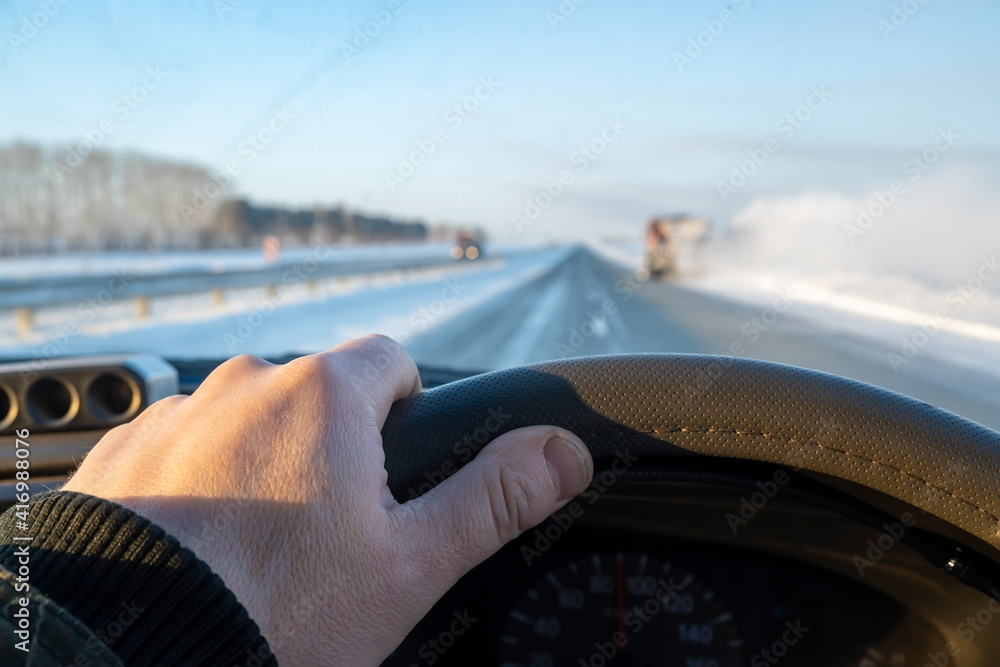 Fototapeta the driver hand is on the steering wheel of a car that is