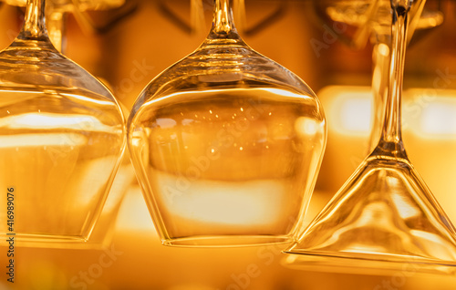 Hanging wine glasses in a bar with beautiful warm lighting photo