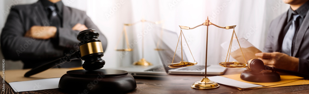 Business and lawyers discussing contract papers with brass scale on desk in office. Law, legal services, advice, justice and law concept picture with film grain effect Business and lawyers discussing contract papers with brass scale on desk in office. Law, legal services, advice, justice and law concept picture with film grain effect