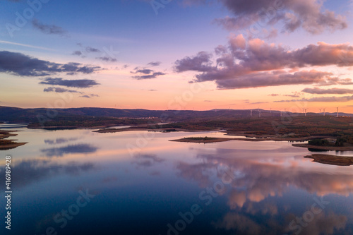 Fototapeta Naklejka Na Ścianę i Meble -  Drone aerial view of a lake reservoir of a dam with perfect reflection on the water of the sunset in Sabugal, Portugal