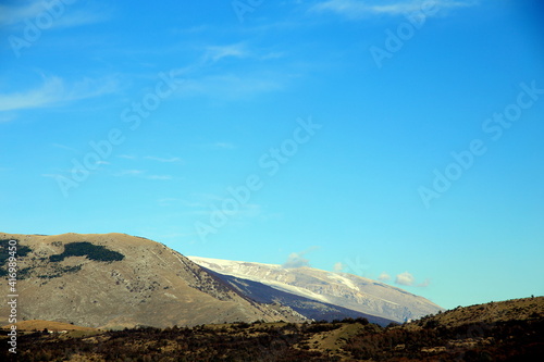 Contrast between still green mountains and snow covered ones in the mountain range photo