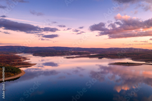 Drone aerial view of a lake reservoir of a dam with perfect reflection on the water of the sunset in Sabugal, Portugal