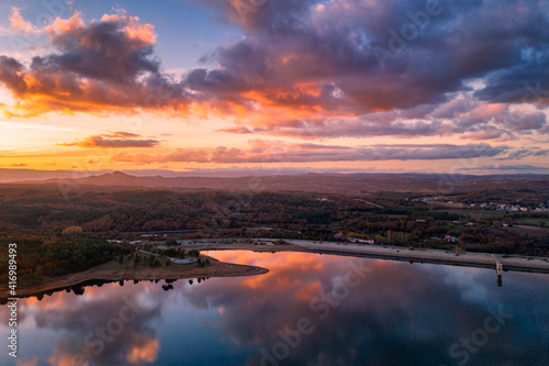 Drone aerial view of a lake reservoir of a dam with perfect reflection on the water of the sunset in Sabugal, Portugal © Luis