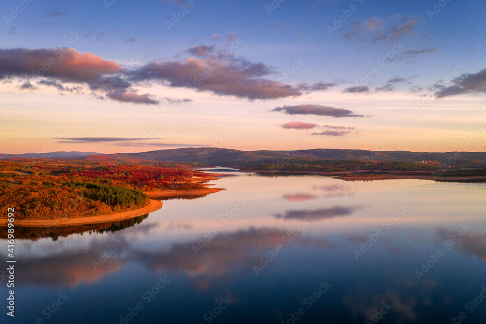 Obraz premium Drone aerial view of a lake reservoir of a dam with perfect reflection on the water of the sunset in Sabugal, Portugal