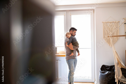 Dad putting to sleep baby boy in his arms at home  © pikselstock