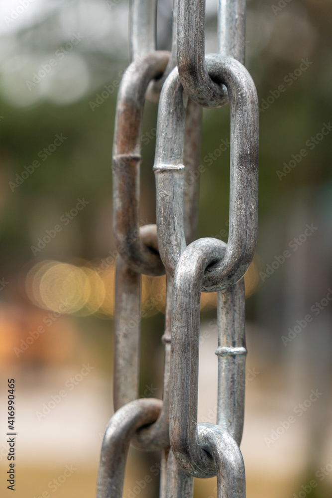 Strong shiny silver chain, outdoors, park background Strong shiny silver chain, outdoors, park background