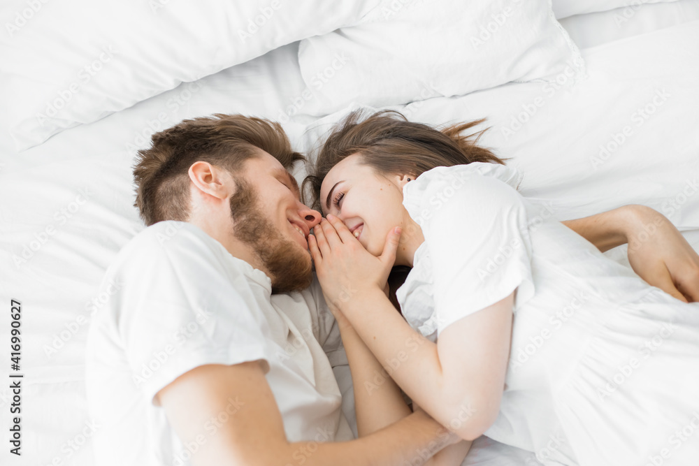 guy and girl lie on a white bed. Flat lay top-down