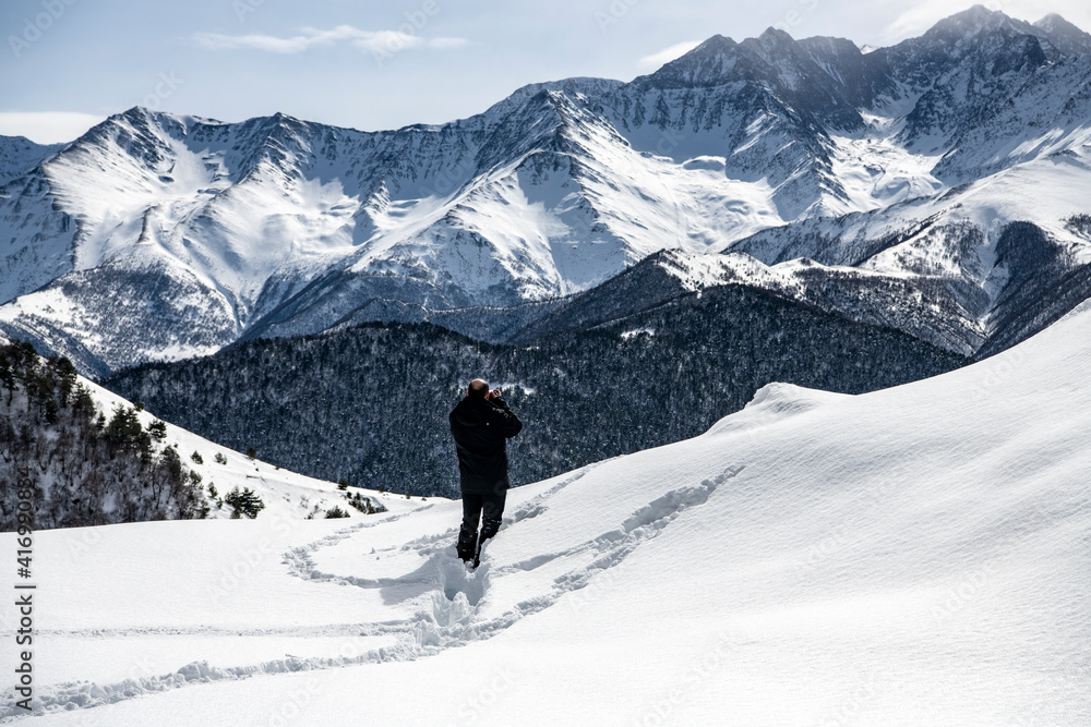 photographer in a black jacket against the background of mountains and gorges against the background of snow