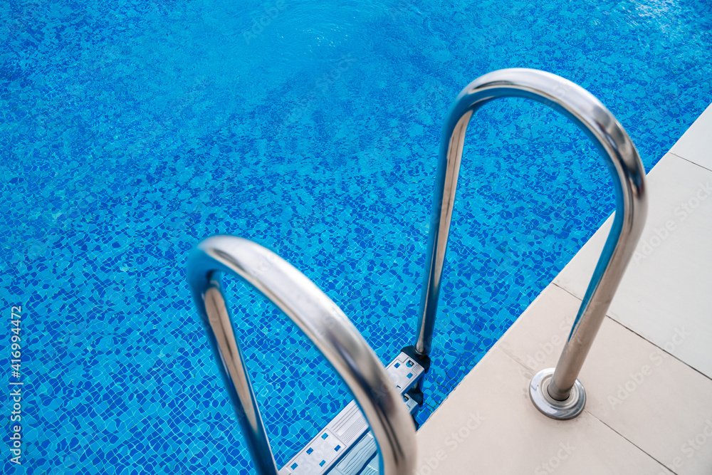 The side of the pool with stairs and tiles. The holiday season is a holiday destination, concept Wallpaper, background, picture without people with empty copy space for your text. The side of the pool with stairs and tiles. The holiday season is a holiday destination, concept Wallpaper, background, picture without people with empty copy space for your text.