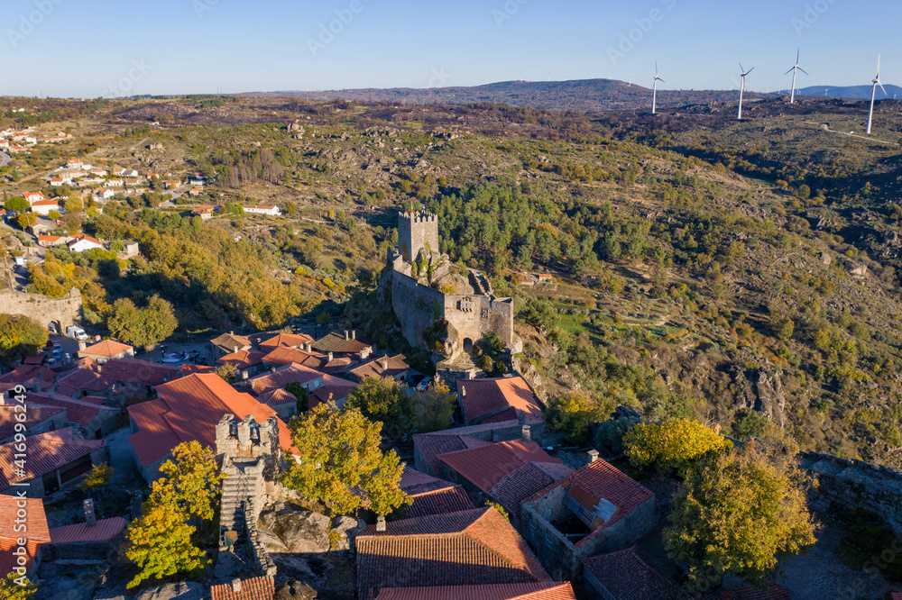 Drone aerial panorama of historic village of Sortelha with castle and with turbines on natural landscape, in Portugal