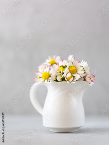 Daisy flowers in a vase on gray background with copy space. minimalist style. Spring holidays concept. Vertical Banner. Soft focus