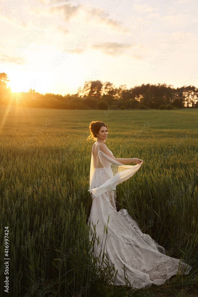 Beautiful young bride in lace wedding dress at the field on the sunset Beautiful young bride in lace wedding dress at the field on the sunset