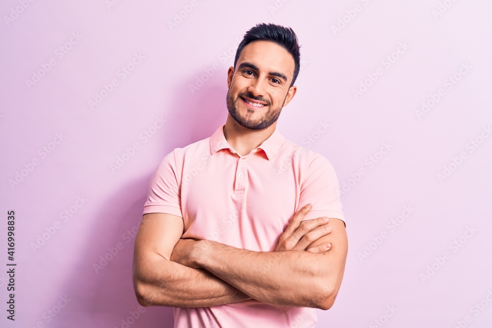 Young handsome man with beard wearing casual polo standing over pink background happy face smiling with crossed arms looking at the camera. Positive person. Young handsome man with beard wearing casual polo standing over pink background happy face smiling with crossed arms looking at the camera. Positive person.