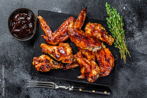 Hot Barbecue chicken wings with sauce bbq. Black background. Top view