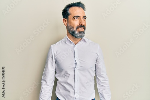 Photography Middle age man with beard and grey hair wearing casual white shirt looking to side, relax profile pose with natural face and confident smile