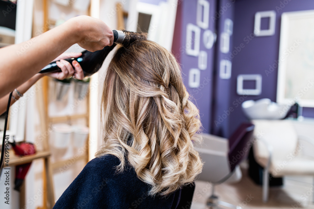 Fototapeta premium Beautiful hairstyle of young adult woman after dyeing hair and making highlights in hair salon.
