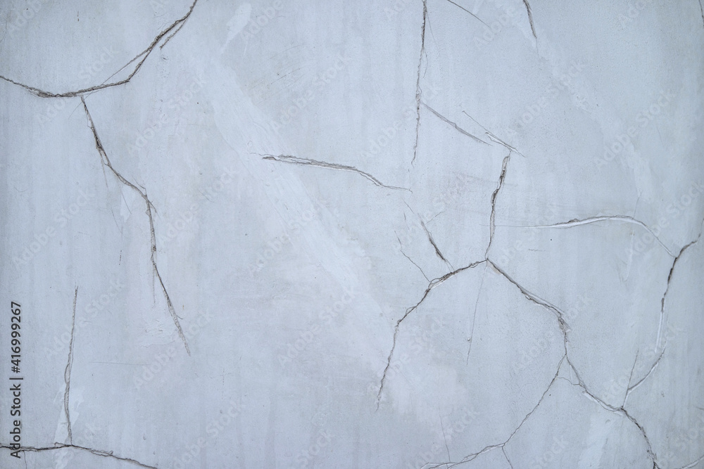 Fototapeta premium Cracks in the white plaster wall