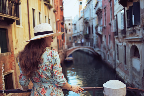 Seen from behind modern tourist woman in floral dress with hat