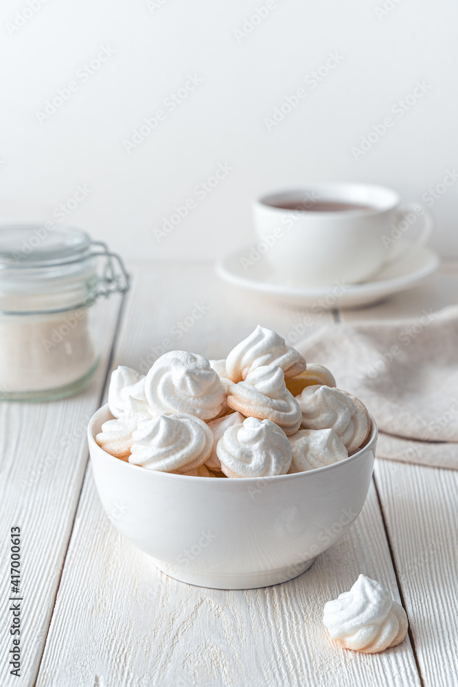 The white plate is filled with delicate, airy meringues on a light background. The white plate is filled with delicate, airy meringues on a light background.
